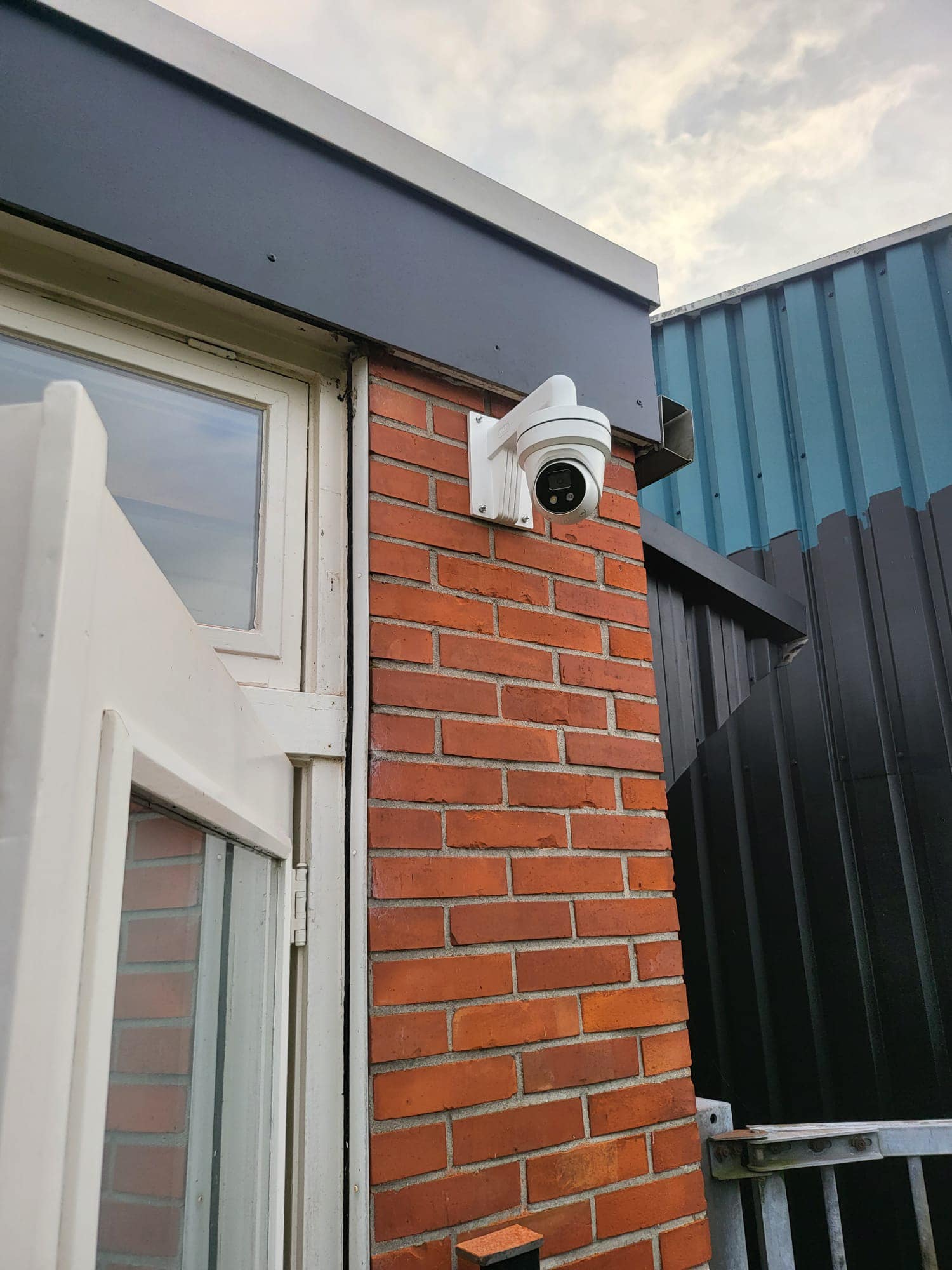 Buitencamera gemonteerd op rode bakstenen muur.